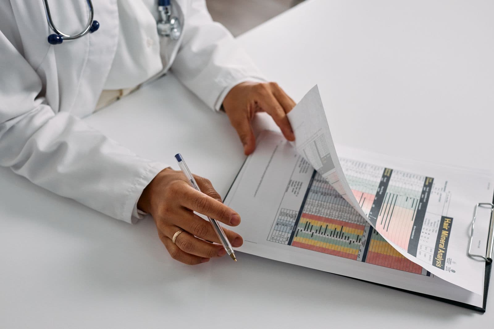 Médico com estetoscópio revisa um relatório com dados e gráficos coloridos, caneta em mão